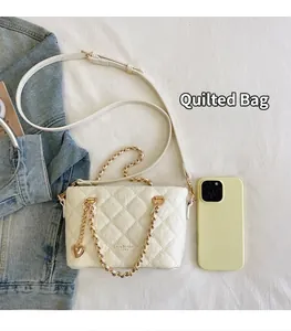 Sac à main matelassé blanc à côté d'un smartphone pour comparer les tailles.