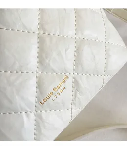 Détail de la texture en cuir blanc matelassé avec logo de marque doré imprimé
