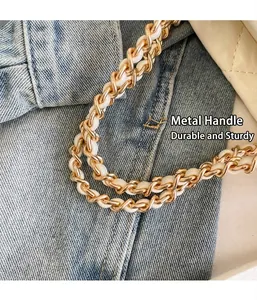 Détail de la bandoulière en chaîne dorée entrelacée de cuir blanc sur un sac seau de luxe