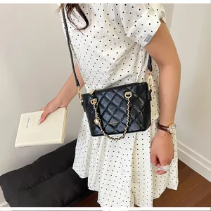 Vue détaillée d'un sac bandoulière matelassé noir porté avec une robe à pois