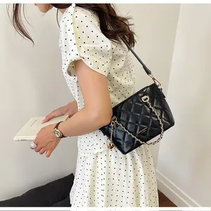 Sac à bandoulière matelassé noir avec chaîne porté par un mannequin avec style