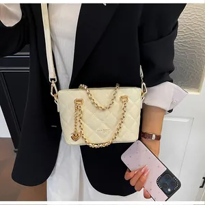 Détail d'un sac seau matelassé couleur crème avec chaîne dorée et breloque cœur élégante