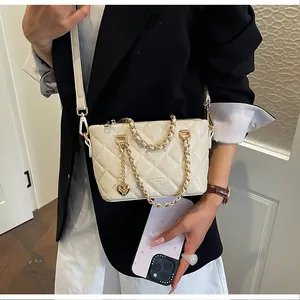 Vue détaillée d'un sac seau matelassé beige avec une chaîne dorée porté par un mannequin