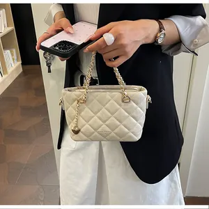 Gros plan d'un élégant sac à main matelassé crème avec une chaîne dorée de luxe.