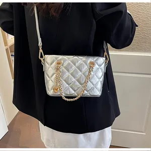 Vue détaillée du sac bandoulière argenté matelassé avec chaîne dorée et breloque cœur.