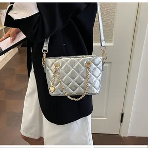 Sac à main matelassé métallisé argenté avec chaîne dorée porté par un mannequin moderne