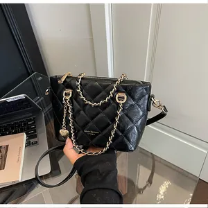 Détail d'un sac seau matelassé noir de qualité supérieure avec chaîne dorée élégante.