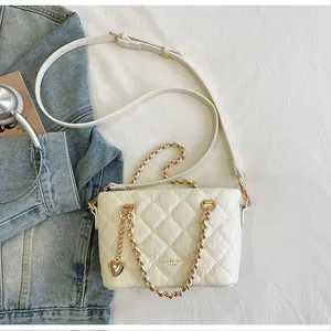 Sac à main blanc matelassé avec chaîne et breloque cœur dorée sur veste en jean