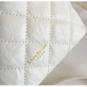 Détail en gros plan d'une texture en cuir matelassé blanc avec logo doré sur un sac seau