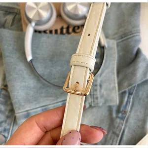 Zoom sur la bandoulière en cuir blanc et la boucle dorée d'un sac seau chic.