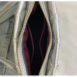 Vue détaillée de l'intérieur d'un sac argenté avec doublure rouge et poche zippée
