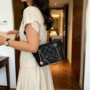 Sac à main en cuir matelassé noir avec chaîne dorée et détail de breloque en cœur