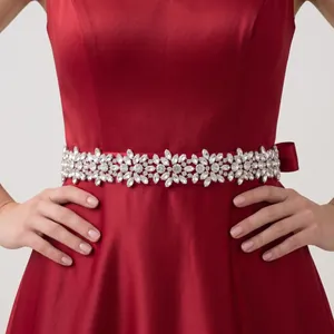 Dettaglio di una cintura da sposa con strass pesanti su un abito di raso rosso.