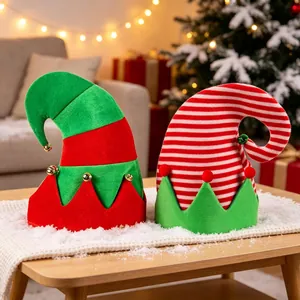Festive red and green striped Christmas elf hats with bells on a snowy wooden table.