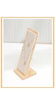 Macro detail of a bamboo necklace display stand with fabric board and elegant pearl decor