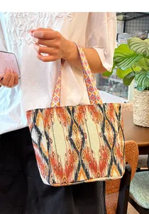 Primer plano de un bolso tote bohemio bordado llevado por una modelo en un café