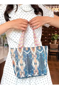 Detalle de un bolso tote retro bohemio con estampados étnicos ikat, llevado por modelo.