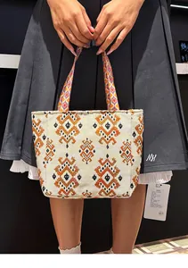 Vista detallada de un bolso tote tejido bohemio con vibrantes patrones geométricos étnicos