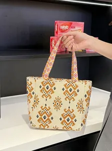 Bolso tote bordado de estilo bohemio con patrones étnicos retro, mostrado llevado en la mano