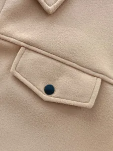 Macro detail of camel colored wool blend coat featuring flap pocket with black button closure