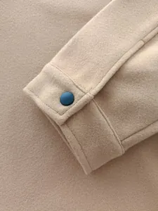 Macro view of camel woolen suit jacket cuff showing fine texture and dark button