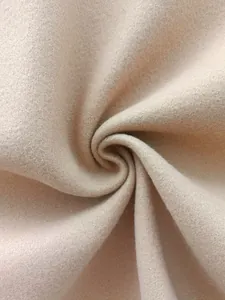 Macro detail of soft beige wool blend fabric showing fine texture and spiral drape