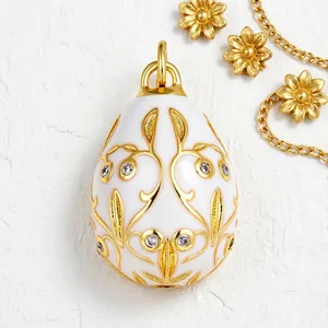 Elegant white enamel egg pendant featuring intricate gold filigree and cubic zirconia