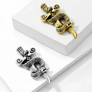 Close-up detail of vintage alloy snake-wrapped sword brooches in gold and silver