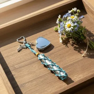 Detail view of a hand-woven blue mesh pouch lipstick holder with silver heart charm