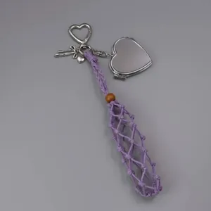 Detail view of purple woven lipstick holder with silver heart-shaped mirror and charms