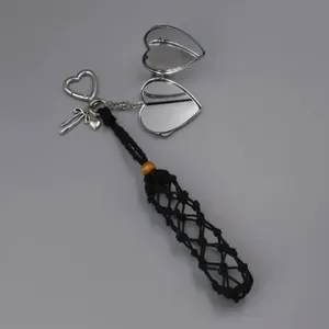 Close-up of handmade black woven pouch keychain with a silver heart locket charm