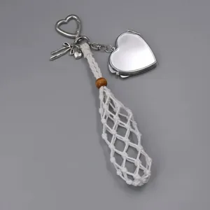 Detail of hand-woven white net pocket with silver heart locket mirror charm