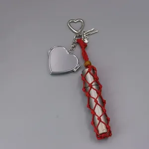 Detail view of a heart-shaped mirror keychain with a red hand-woven mesh lipstick holder.