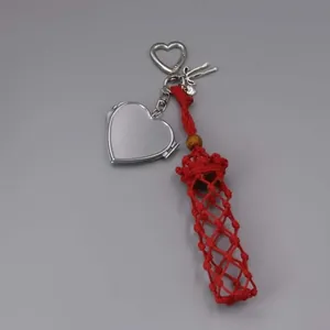 Detailed view of red hand-woven lipstick pouch with silver heart mirror charm