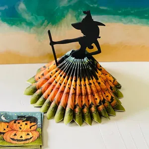 Close-up of witch napkin holder with pumpkin patterned napkins forming a skirt