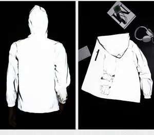 Detailed macro view of high-visibility reflective hooded outdoor windbreaker in the dark