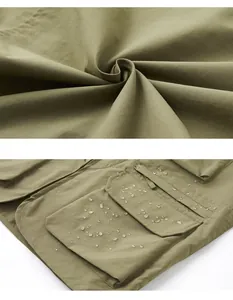 Gros plan du tissu déperlant durable et des poches d'un gilet utilitaire d'extérieur vert.