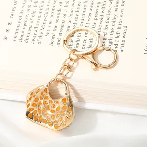Detail shot of a golden alloy handbag keychain with intricate orange cutout patterns.