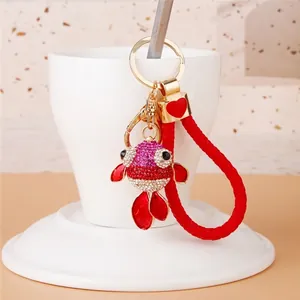 Close-up of a sparkling rhinestone goldfish keychain with a red braided loop charm