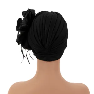 Back view of elegant black turban hat with large side flower and ribbon streamers.