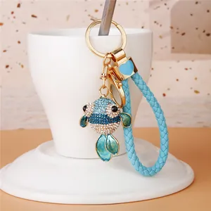 Close-up view of a cute blue rhinestone fish keychain featuring a light blue woven strap