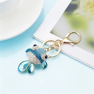 Close-up of a sparkling blue and white rhinestone goldfish keychain charm with gold hook