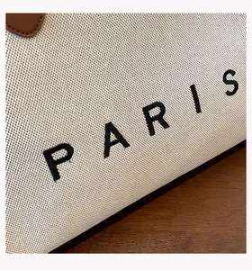 Macro detail of PARIS letter embroidery on textured canvas tote bag fabric