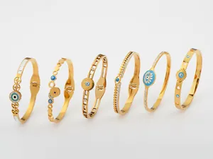 Vista dettagliata di sei braccialetti in acciaio al titanio placcati oro con motivi occhio