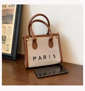 Detail of the stylish canvas tote bag featuring 'PARIS' print and brown leather trim.