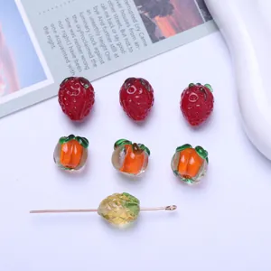 Detailed macro view of handmade fruit-shaped glass beads including strawberries
