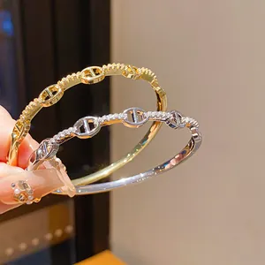 Λεπτομέρεια επιχρυσωμένων βραχιολιών 18K με ζιργκόν και πολυτελές σχέδιο κρίκων.