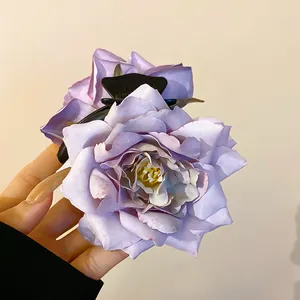 Détail en gros plan d'une pince à cheveux rose en tissu violet tenue par une main, chic.