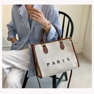Lifestyle shot showing the Paris print detail on a canvas tote bag held by a model