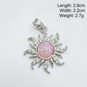Détail d'un pendentif fleur de soleil vintage avec opale rose et pierres étincelantes.